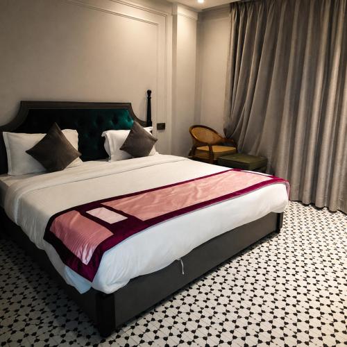 a bedroom with a large bed and a window at Hotel The Palassio in Kānpur