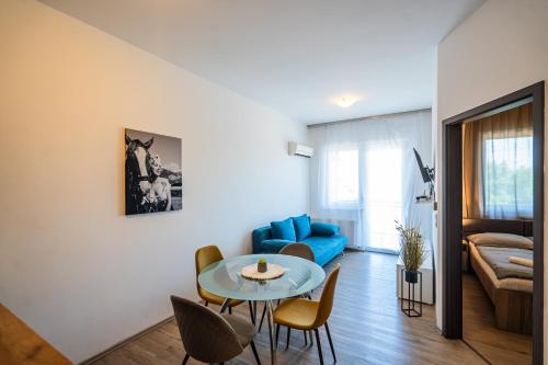 a living room with a blue couch and a table at AH-Corso Wellness Panorama Apartman in Siófok
