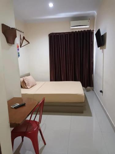 a bedroom with a bed and a desk and a chair at Legenda Beril Hostel in Makassar