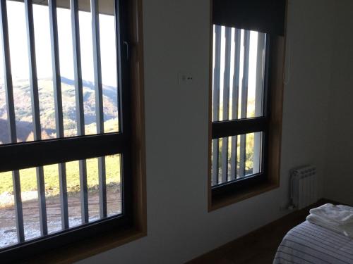 two windows in a bedroom with a view of a mountain at Linar Do Rei in Linares