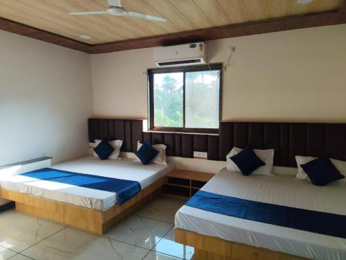two beds in a room with a window at Patidar Villa Mount Abu in Mount Ābu