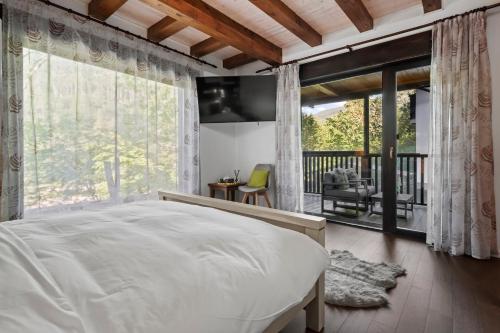 a bedroom with a large bed and a balcony at Drago Chalet Sinaia, hot tub and sauna in Sinaia