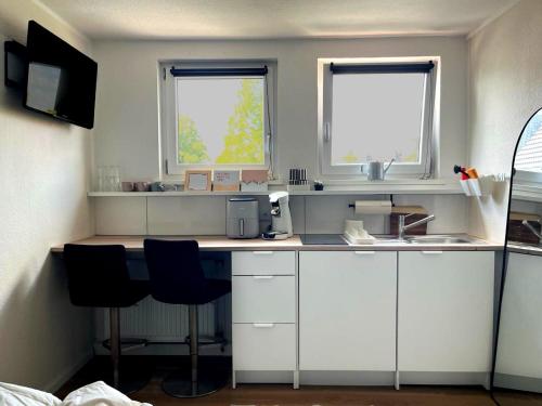 a kitchen with white cabinets and two windows at Stadtquartier Soest in Soest