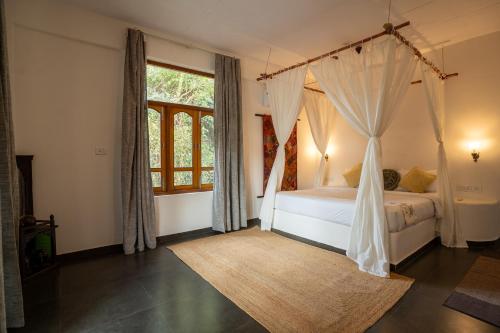 a bedroom with a canopy bed and a window at Alpa Viram Retreat Goa in Mandrem