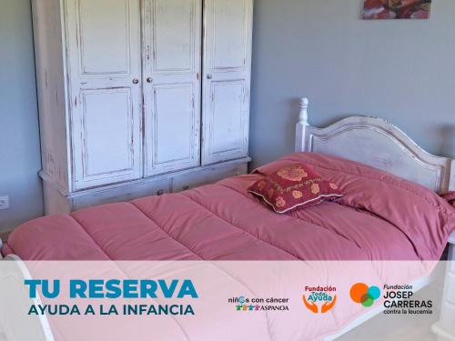 a bed with a pink comforter on top of it at Apartamentos La casa del Zapatero in Corvera