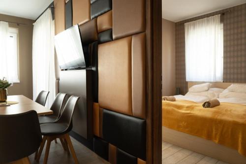 a bedroom with a bed and a table and a dining room at AH-Corso Wellness Residence in Siófok