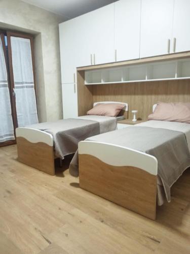 two beds in a room with wooden floors at Pimpus in Cicciano