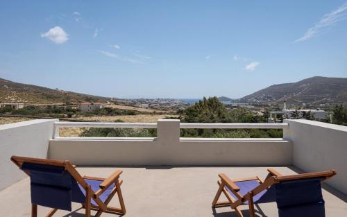 a pair of chairs on the balcony of a house at Andros Royal Villa in Koumárion