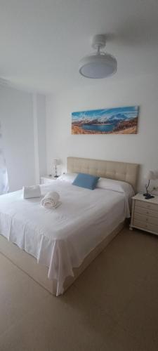 a bedroom with a large white bed with a painting on the wall at Complejo Vallsun in Estepona