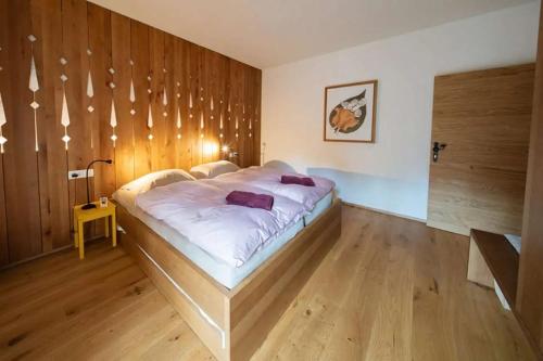 a large bed in a room with a wooden wall at Hiša Tam Čez in Slovenj Gradec
