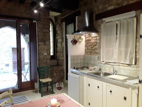una cucina con lavandino e tavolo con bicchiere di vino di Vico Del Poeta ad Assisi