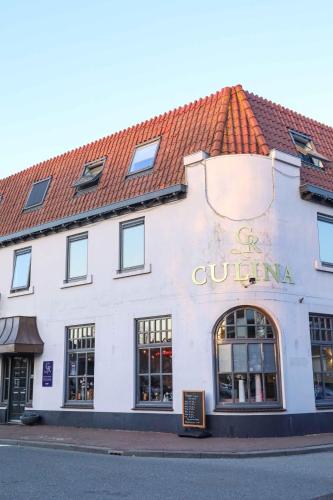 a white building with a red roof on a street at Boutique Hotel Enkhuizen in Enkhuizen