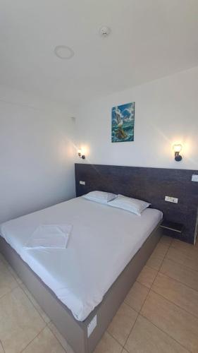 a bed in a bedroom with two lights on the wall at Vila Arthur in Eforie Nord