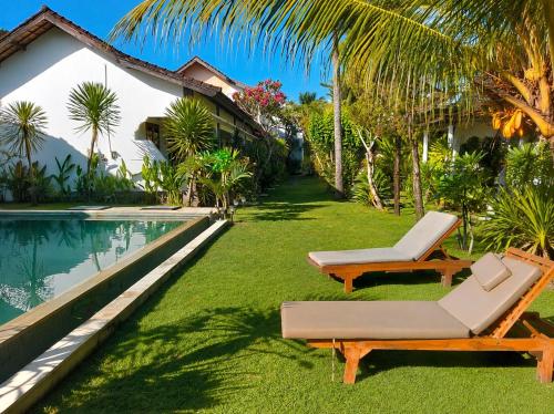a yard with two lounge chairs and a swimming pool at The Confidential Mandalika - Sea Front Hotel - New Starlink 70Mbps WiFi - Free Gym Access in Kuta Lombok