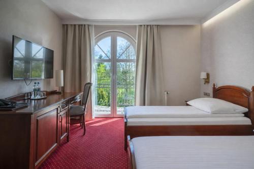 a hotel room with two beds and a desk and a window at Dworek Skawiński in Skawina