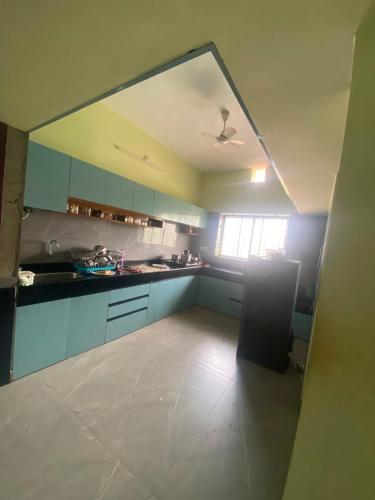 a large kitchen with blue cabinets and a window at Siya's home in Udupi