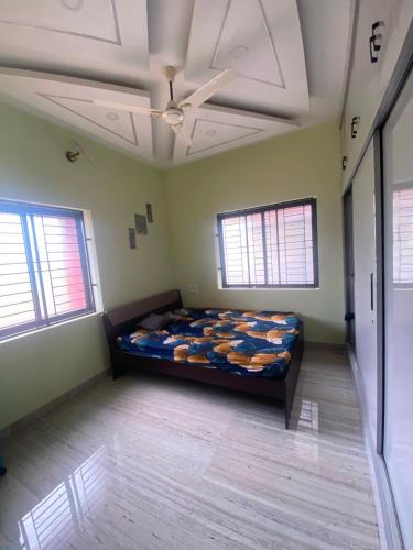 a bedroom with a bed in a room with two windows at Siya's home in Udupi