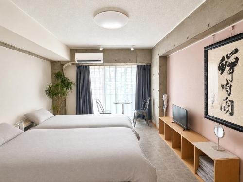 a hotel room with two beds and a tv at Eight One in Osaka