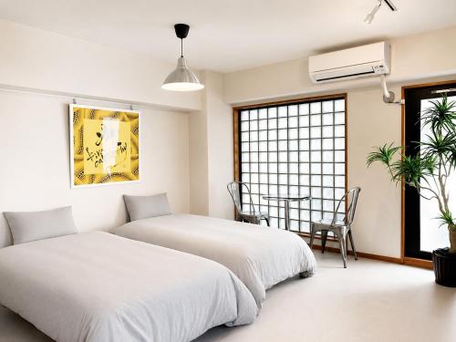 two beds in a room with a table at Eight One in Osaka