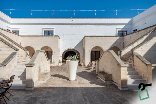 a courtyard of a building with stairs and a vase at Hotiday Fasano Mare in Savelletri di Fasano