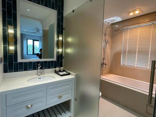 a bathroom with a sink and a mirror and a tub at Ocean Homes cơ sở SH24 in Ðình Loan