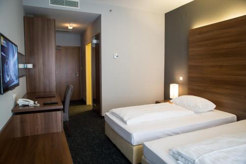 a hotel room with two beds and a flat screen tv at Hotel Sliško in Zagreb