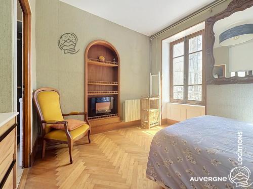 a bedroom with a bed and a chair and a fireplace at Le Chardonneret du Sancy in Montaigut-le-Blanc