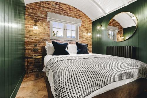 a bedroom with green walls and a bed with a mirror at Nestledstays - The Hide in Walberton