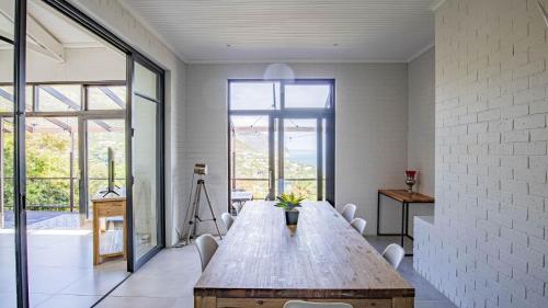 a large wooden table in a room with windows at Sunset Bay Stay in Hout Bay