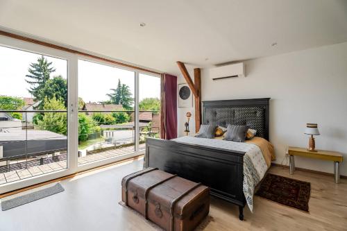a bedroom with a large bed and large windows at La Grange in Reichstett