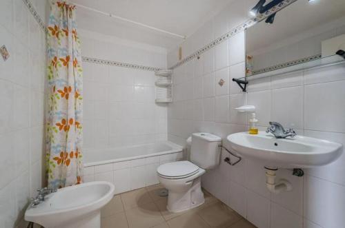 a white bathroom with a toilet and a sink at oceano de bajamar in Bajamar