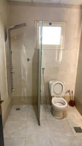 a bathroom with a toilet and a shower with a window at عز الاصالة للشقق المخدومة تصنيف اقتصادي in Taif
