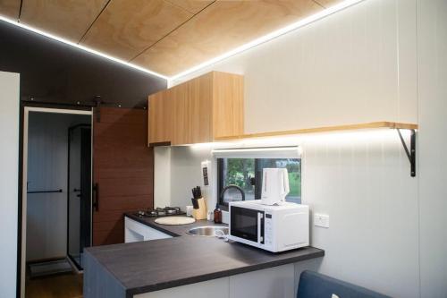 a kitchen with a microwave on top of a counter at The Lorikeet Tiny Home with Stunning Views in Canoelands
