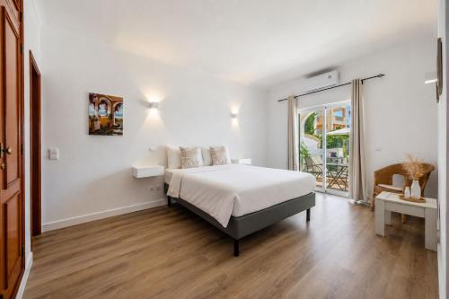 a white bedroom with a bed and a large window at Luz Sun Poolhouse in Luz