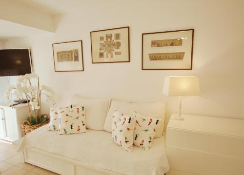 a living room with a white couch with two pillows at Le Studio des Deux Frontières in Beausoleil