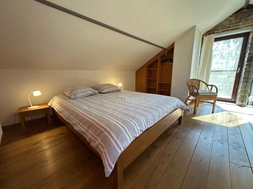 a bedroom with a bed and a chair and a window at Le Fournil d Andrimont in Stoumont