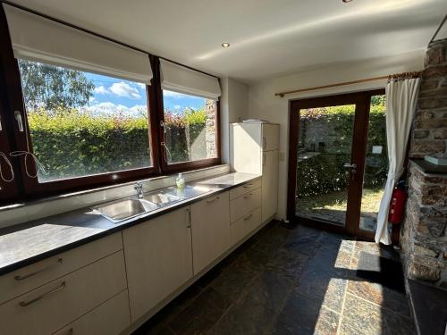 a kitchen with a sink and two windows at Le Fournil d Andrimont in Stoumont