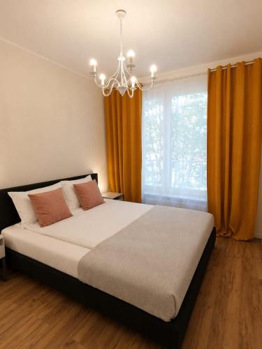 a bedroom with a bed with orange curtains and a chandelier at JBHotels Apartament DeLuxe przy Galaxy in Szczecin