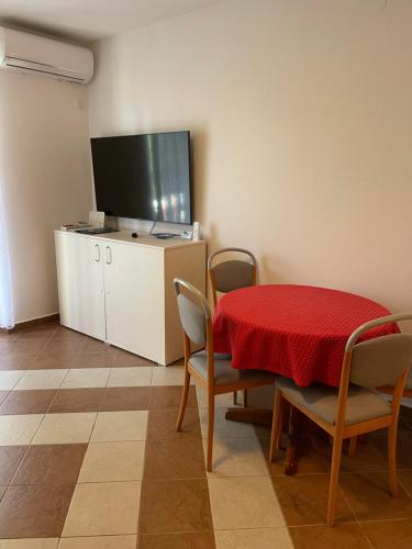 a dining room with a red table and chairs and a television at Na-Vi in Novi Vinodolski