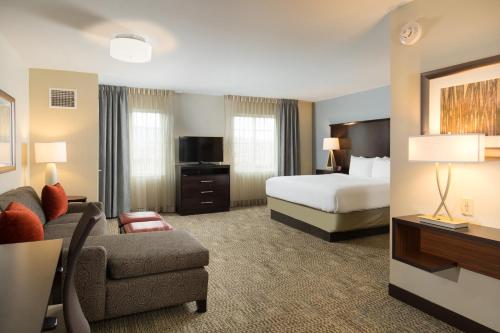 a hotel room with a bed and a couch at Staybridge Suites Corona South, an IHG Hotel in Corona