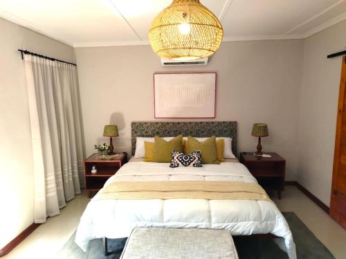 a bedroom with a large bed and a chandelier at Riverside Cottages in Graaff-Reinet