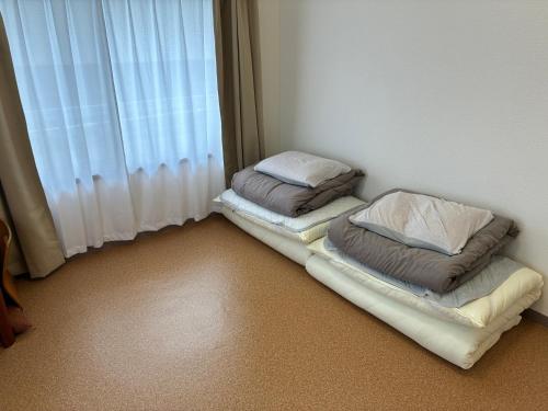 two beds in a corner of a room with a window at apartment hotel myu in Mito