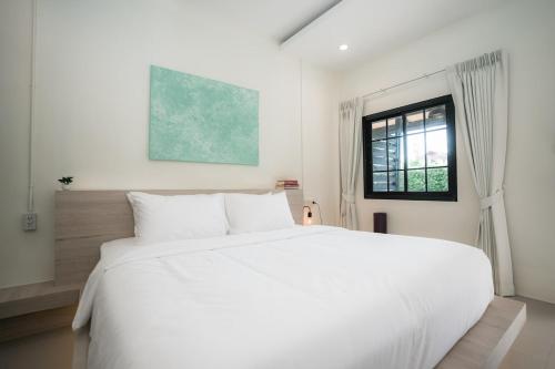 a white bed in a white bedroom with a window at Sandana Studio Apartments - Studio 2 in Nathon Bay