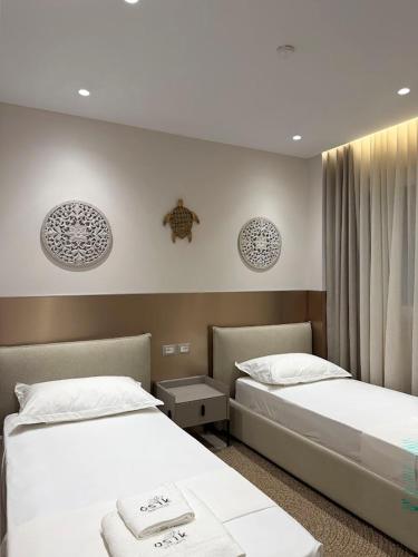 two beds in a hotel room with white sheets at Osik apartments villa 01 in Golem