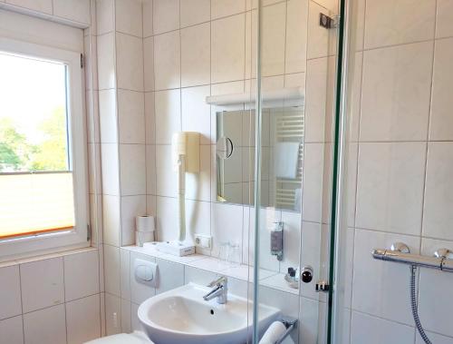 a bathroom with a sink and a glass shower at Hotel Waldhorn in Friedrichshafen
