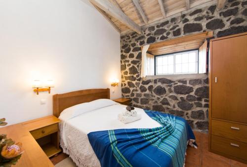 um quarto com uma cama e uma parede de pedra em Casa do Alambique em Santa Luzia