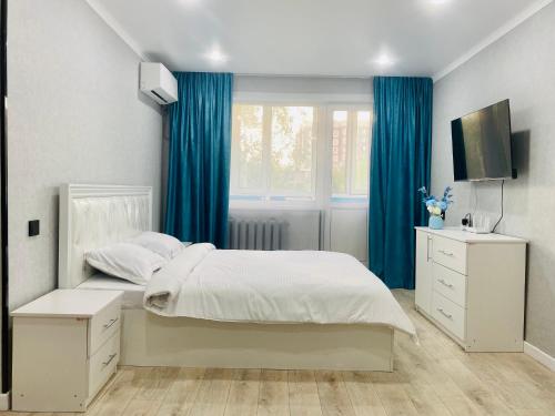 a bedroom with a bed with blue curtains and a window at Elegant Home Apart in Karagandy