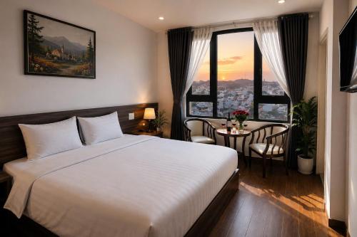 a hotel room with a bed and a table with chairs at Laimeront Hotel Dalat Vietnam in Da Lat