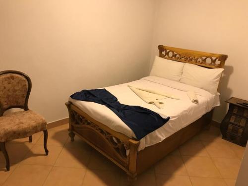 a bed with a wooden frame and a chair in a room at Guest House in Luxor
