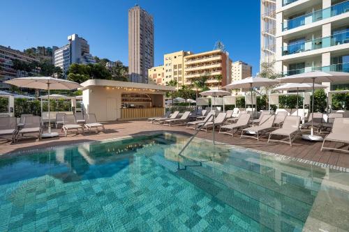 a swimming pool with lounge chairs and umbrellas at Port Benidorm Hotel & Spa 4* Sup in Benidorm